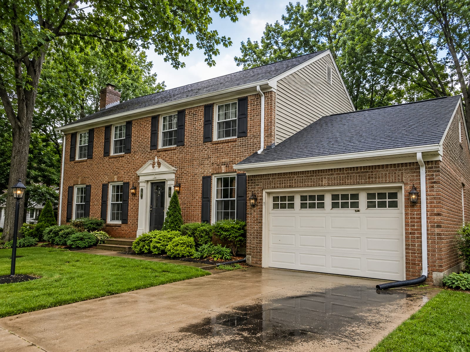 Wide view of a brick colonial home with clean, debris-free gutters along the roofline after service