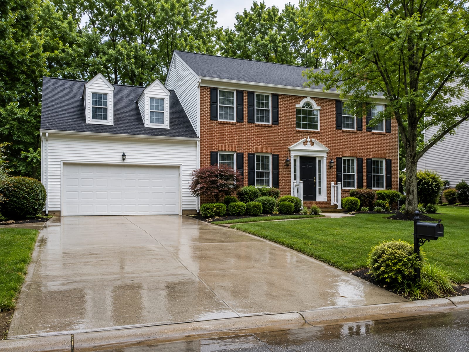 Wide view of a freshly pressure washed brick and vinyl-sided colonial home in a Nottingham Maryland suburban neighborhood with clean driveway and lush green landscaping