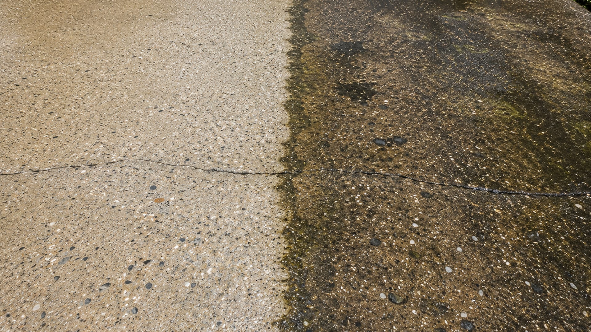 Close view of a residential concrete driveway in Perry Hall Maryland showing a sharp clean line between a freshly pressure washed section and a stained weathered section
