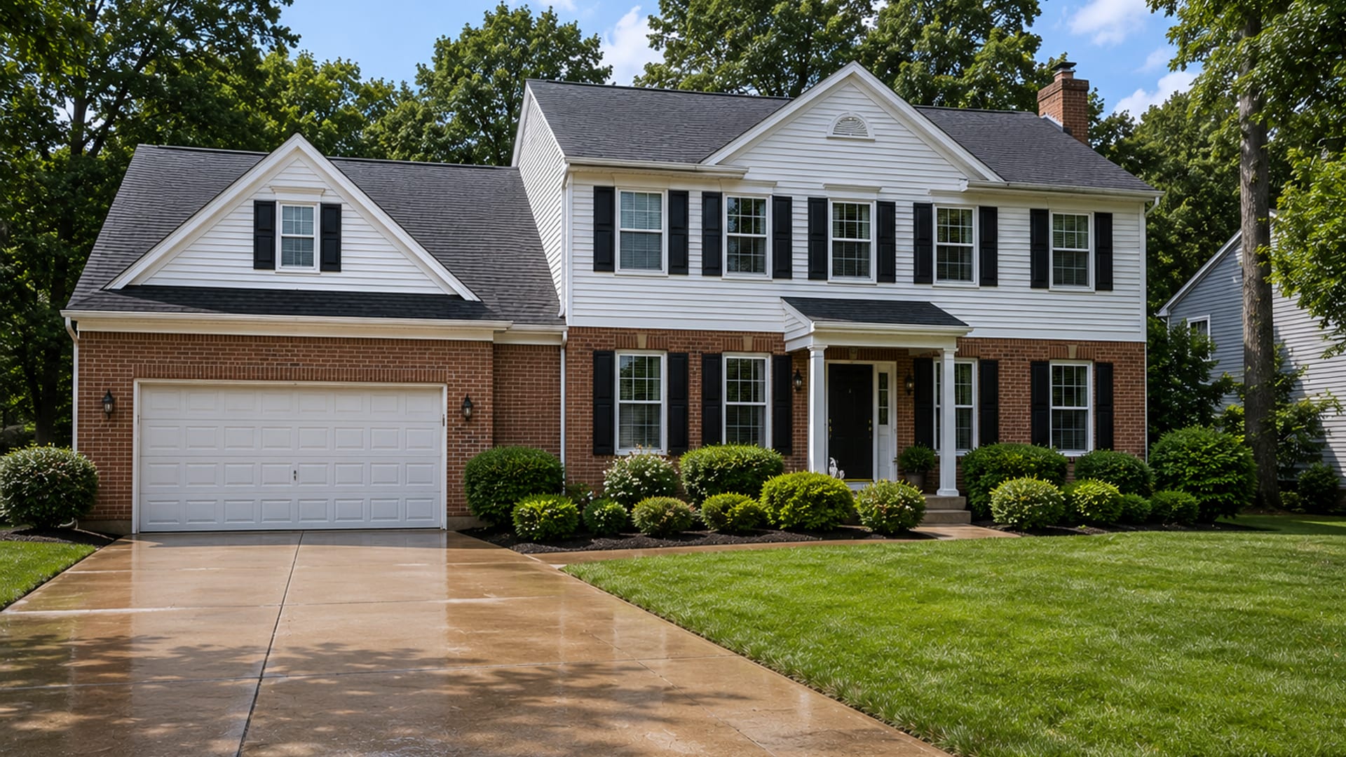 Wide shot of a freshly pressure washed brick and vinyl sided colonial home in a Baltimore County suburb with a clean driveway, bright siding, and lush green landscaping under natural daylight
